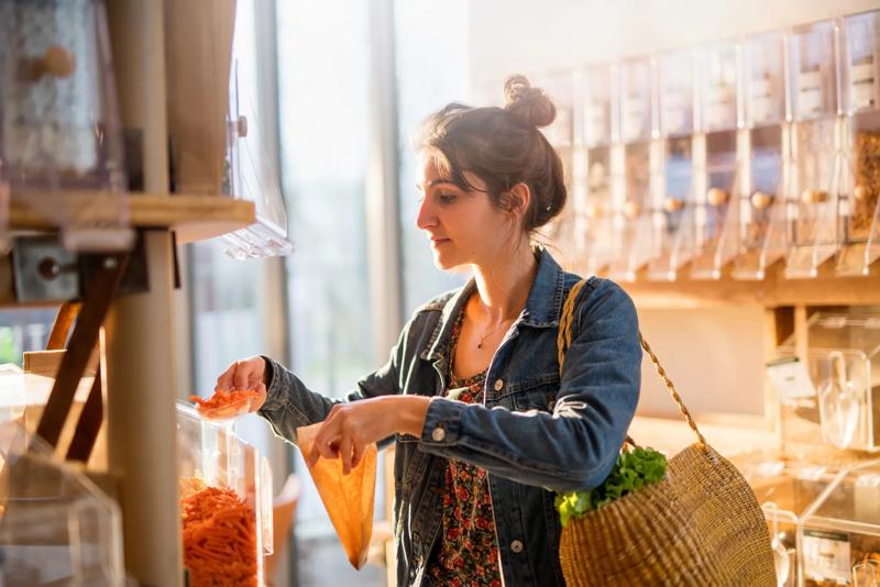 Beautiful young woman shopping in a bulk food store. She buys organic pasta